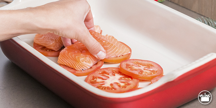 Colocar sobre las rodajas de tomate los cuatro lomos de salmón con la piel hacia abajo.