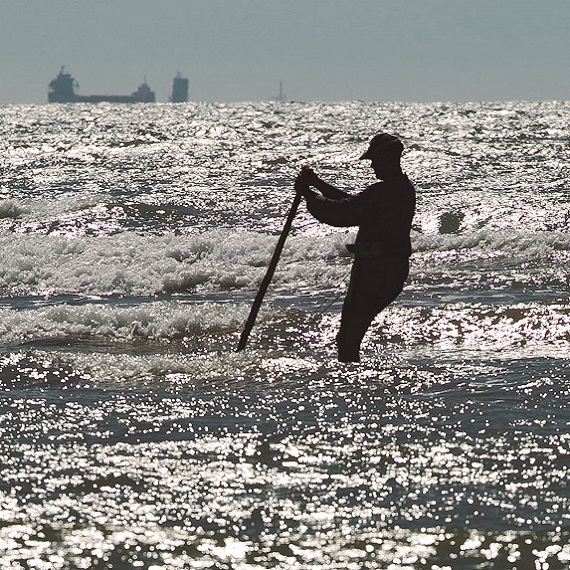 Pescador a varear na auga.